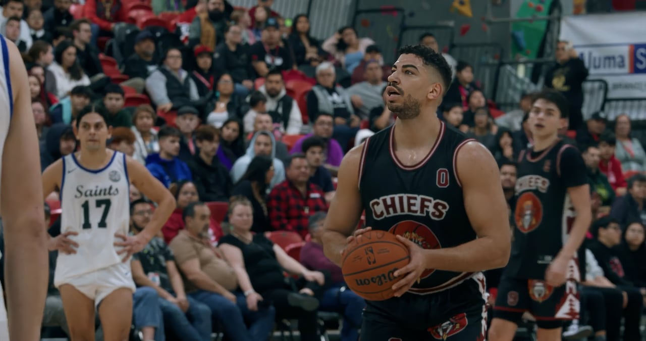 A man in a basketball uniform standing in front of a crowd. looks as if he is about to take a shot.