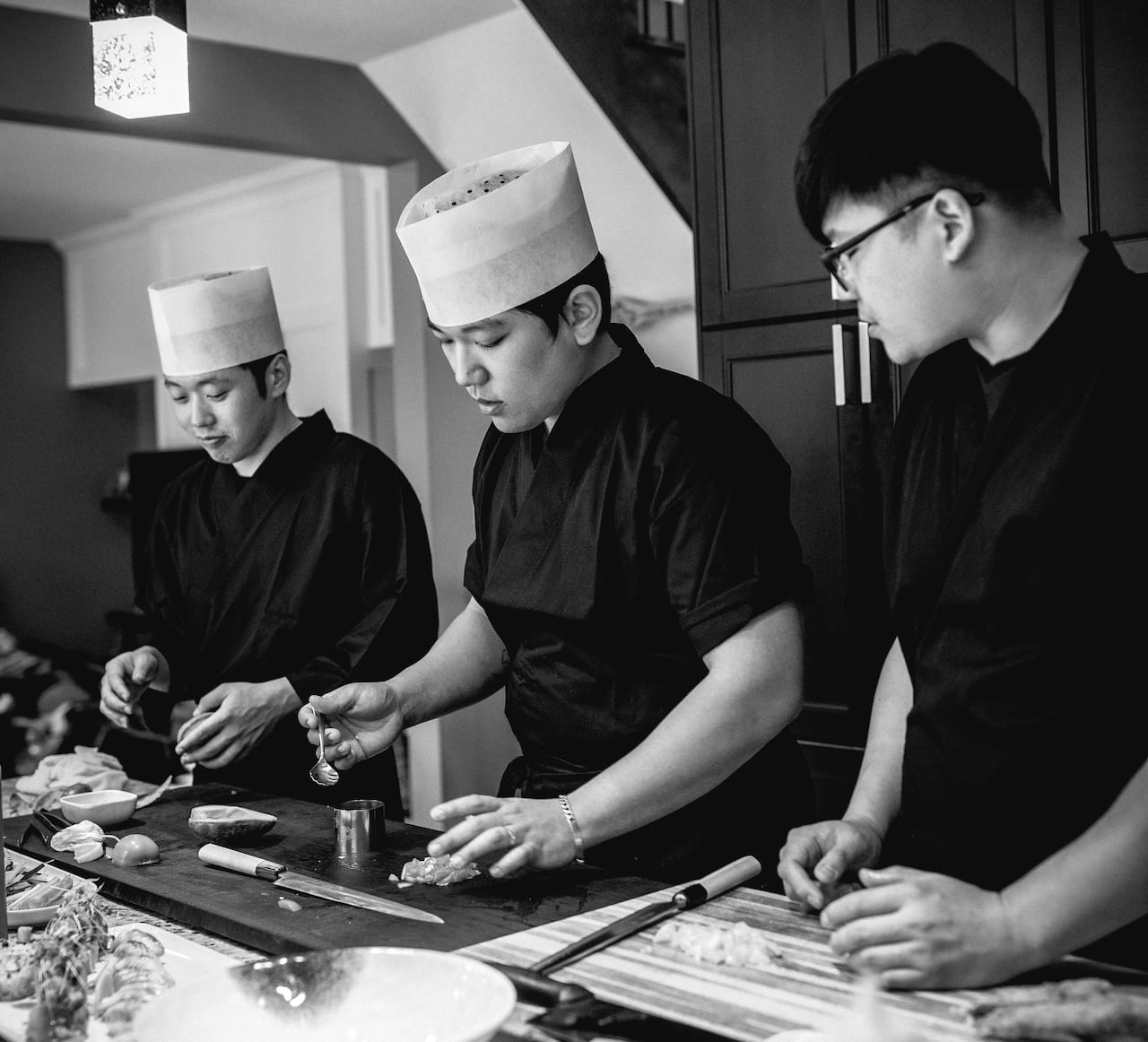 3 sushi chefs preparing food. Black and white photo