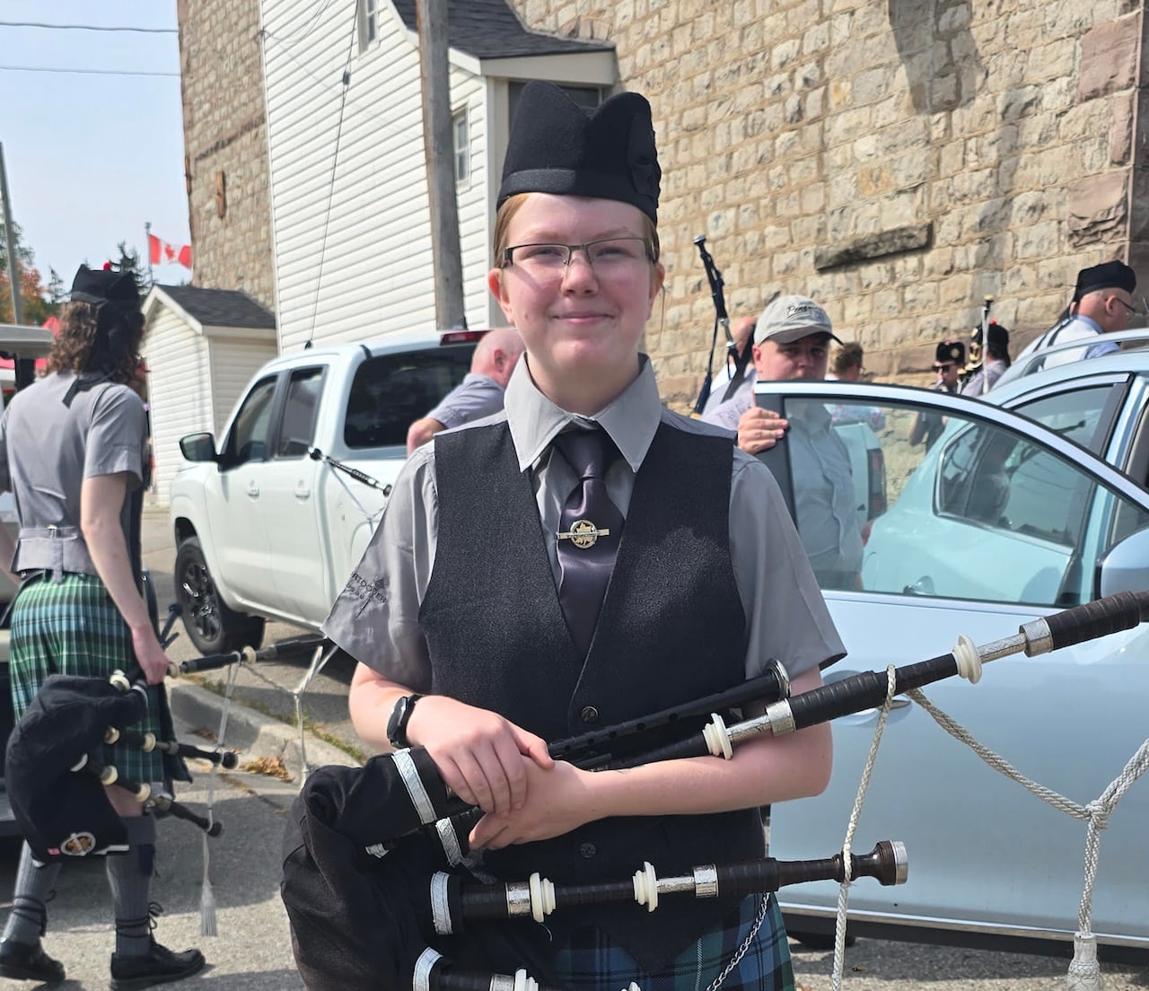 girl stands in band uniform holding bagpipe