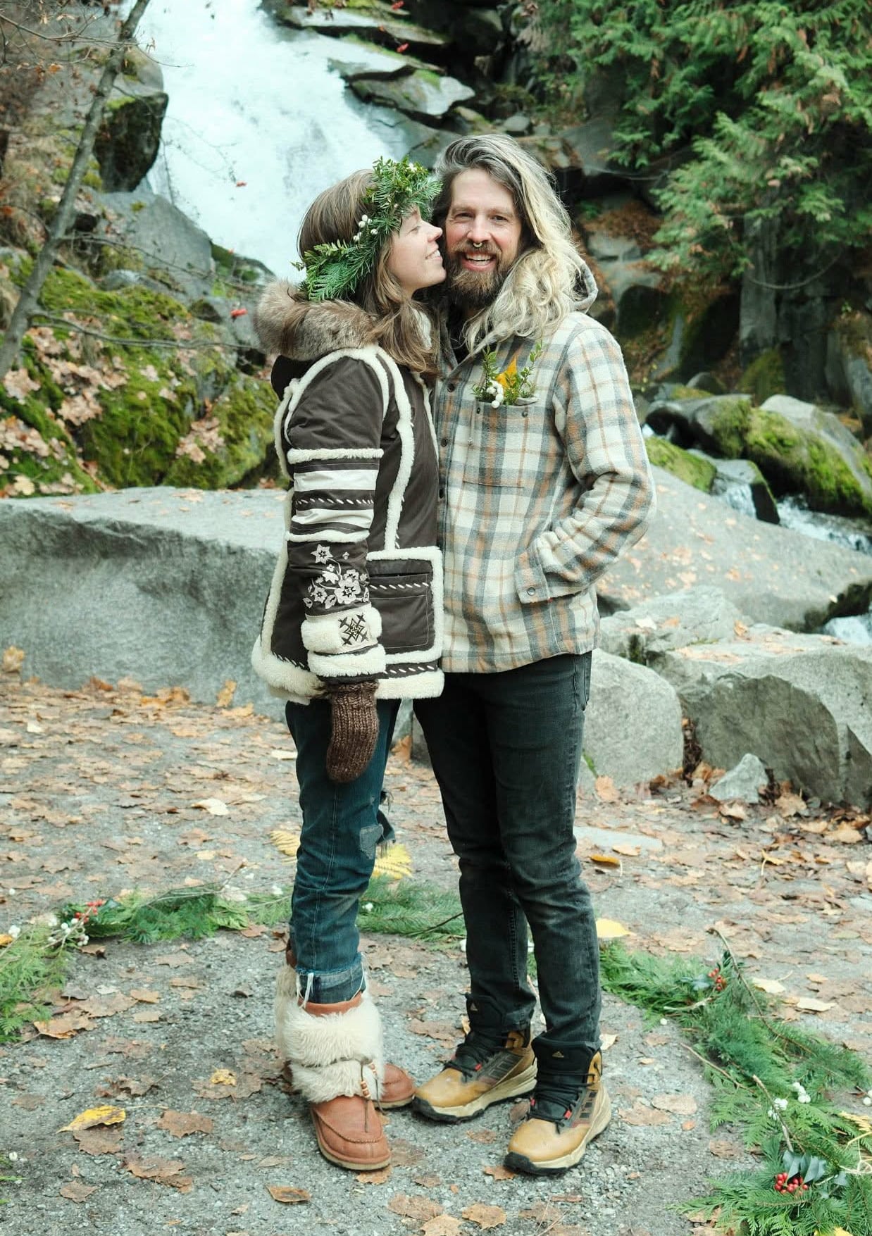 A woman smiles as she leans in toward a man as they stand in front of a small waterfall