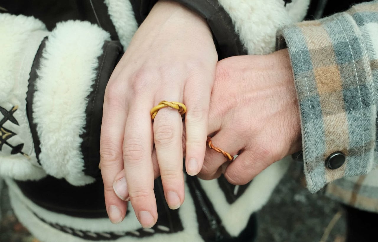 Two people's hands are shown wearing rings made from trees