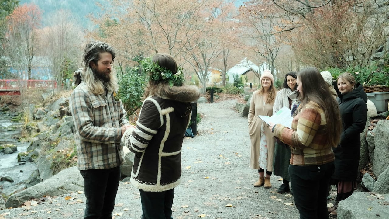 Two people stand holding hands while others look on