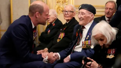 PA Media Prince William smiles as he chats with veterans at a reception for veterans who served in the Pacific during World War Two, part of the commemorations marking the 80th anniversary of VJ Day, at Windsor Castle. The veterans feature wear their military service medals on dark jackets. 