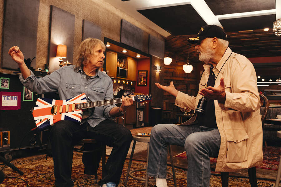 Marti DiBergi inrerviewing Nigel Tufnel, who is holding a guitar
