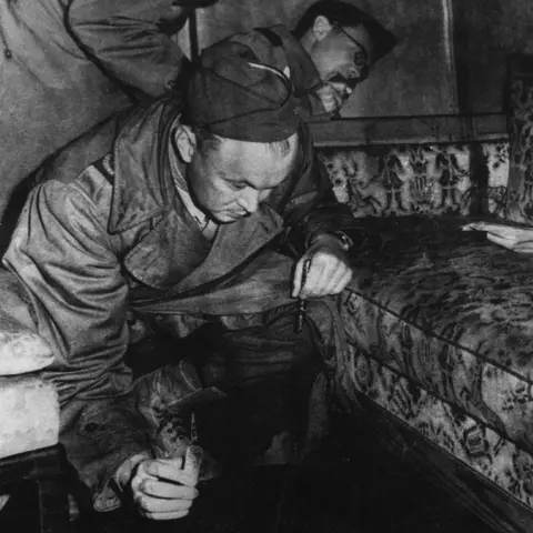 Alamy Black and white image of a man inspecting the couch