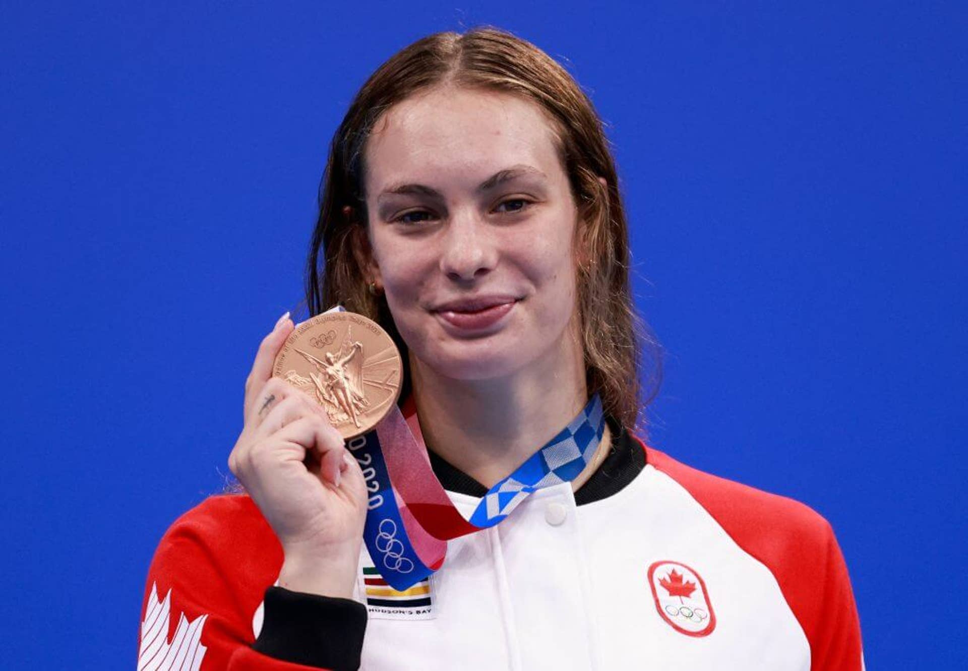 Canadian swimmer Penny Oleksiak lifts her bronze medal while posing for a photo during the Tokyo Olympics in 2021.