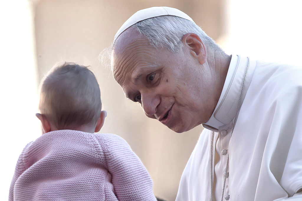 Pope Leo XIV greets a child as he arrives for a Jubilee