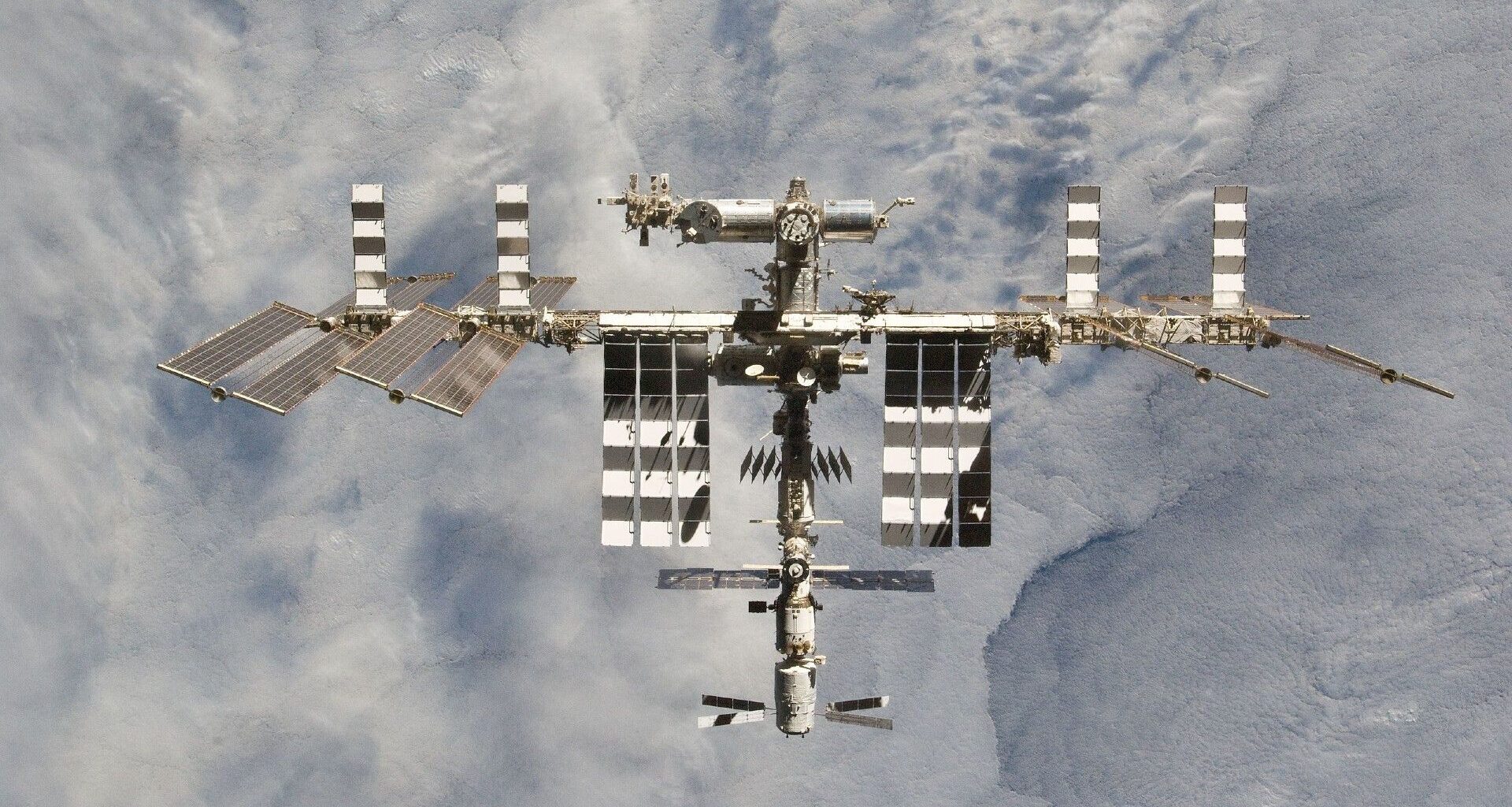 A photo of a large space station with various solar panels floating above Earth.
