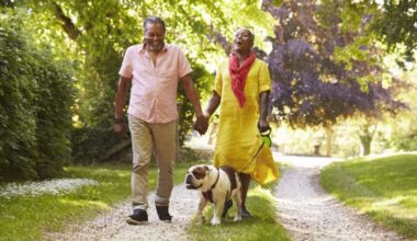 Senior Couple Walking With Pet Bulldog In Countryside