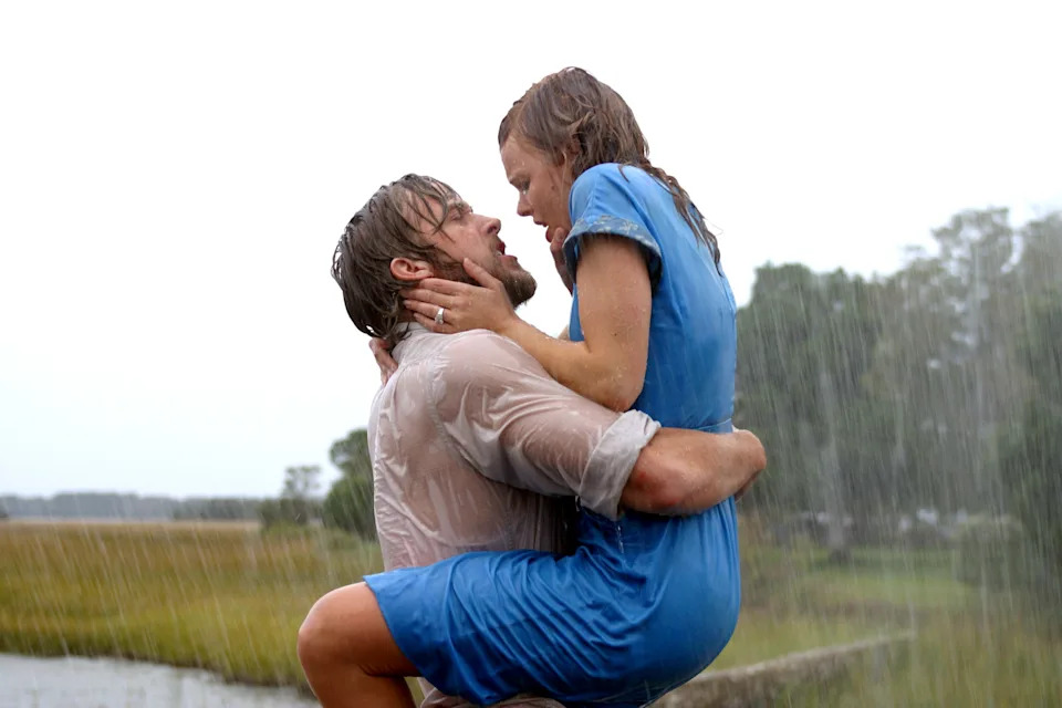 A couple passionately embraces in the rain, with the man lifting the woman as they gaze into each other's eyes