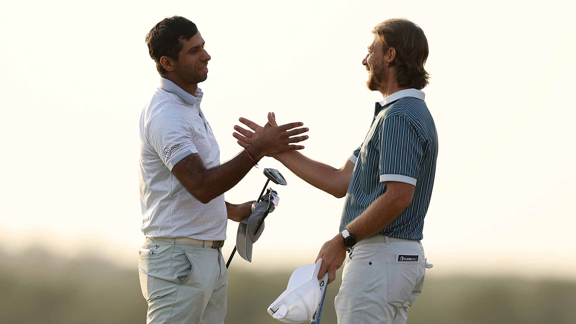 Aaron Rai and Tommy Fleetwood embrace on the 18th green at the 2025 Abu Dhabi HSBC Championship.