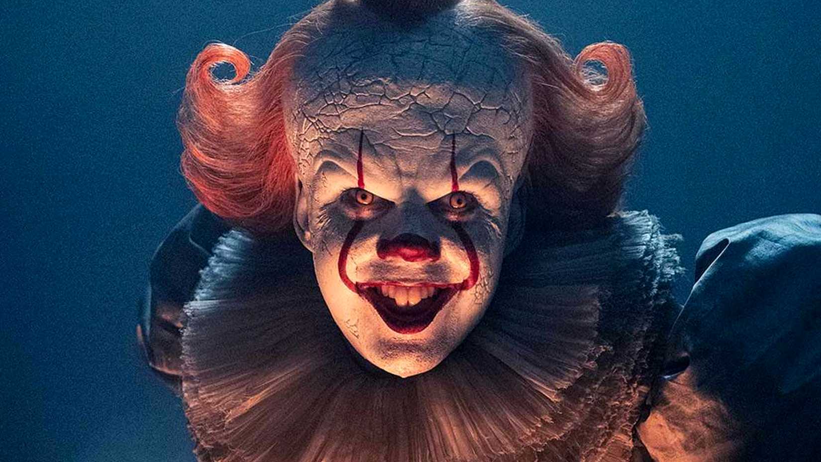 Bill Skarsgard's Pennywise smiles under sinister lighting in It Welcome to Derry