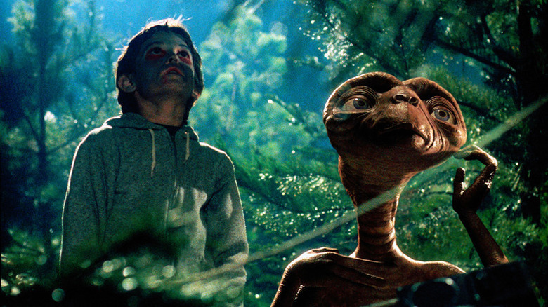 Elliott Taylor (Henry Thomas) and E.T. look up at a light in a forest in E.T. the Extra-Terrestrial