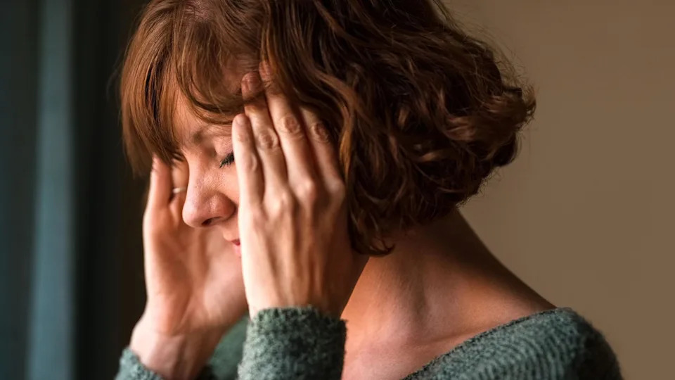 A middle-aged woman holding her head