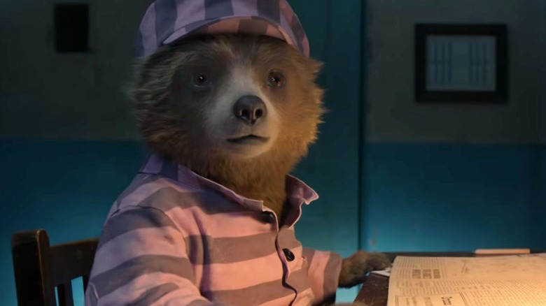 Paddington (Ben Whishaw) reads a newspaper in his pink prison uniform in Paddington 2