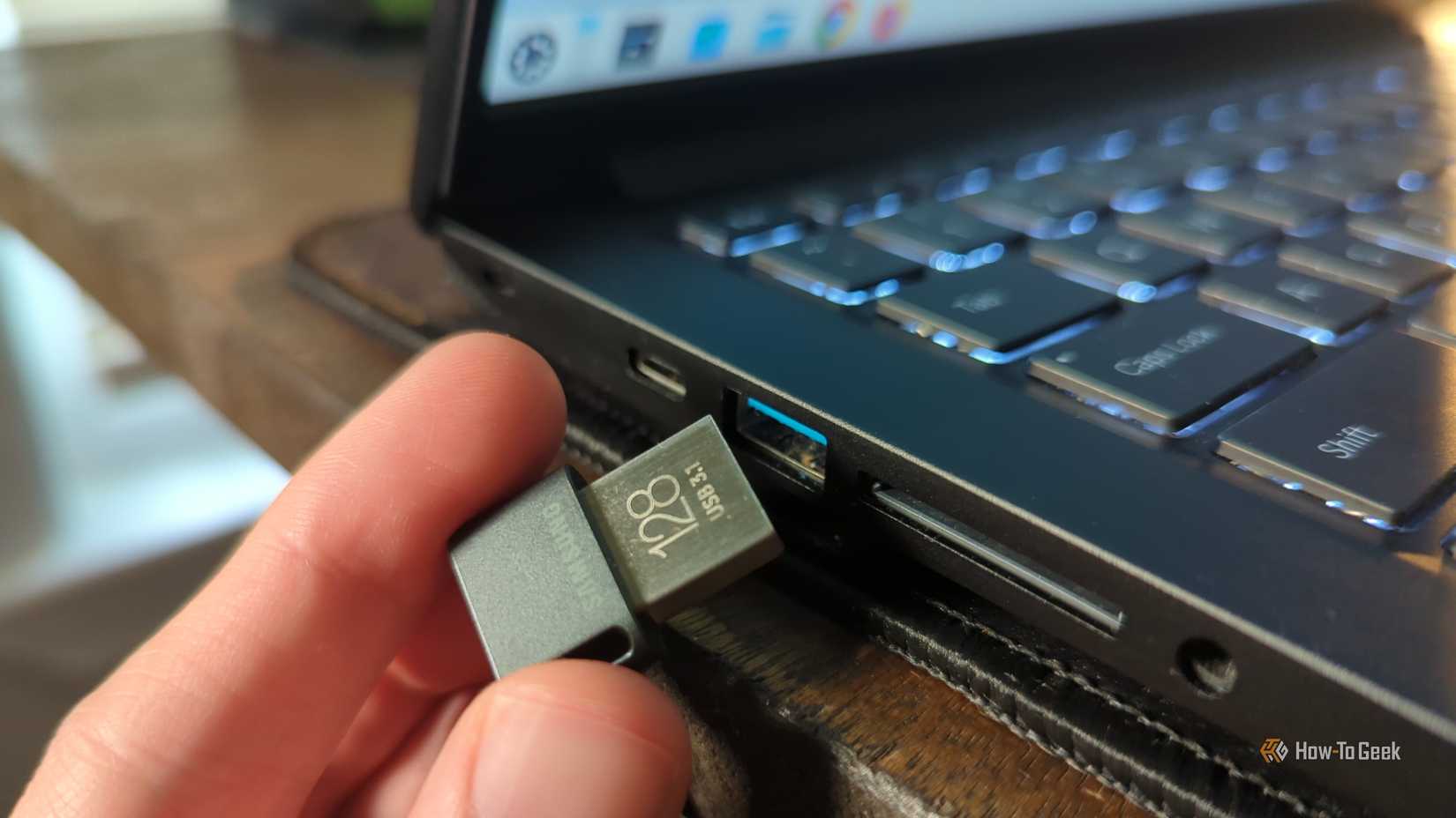 Person's hand putting a USB drive in a laptop port.