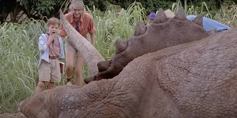 Joseph Mazzello as Tim Murphy and Laura Dern as Ellie Sattler look at triceratops in Jurassic Park
