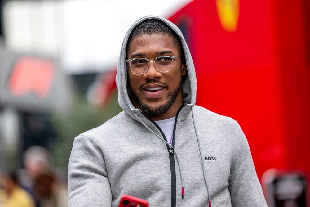 Anthony Joshua smiling as he walks down the street, projecting confidence ahead of his high-stakes fight against Jake Paul, which carries a record-breaking $92 million payday.
