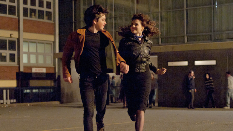 Conor Lalor (Ferdia Walsh-Peelo) and Raphina (Lucy Boynton) run smiling and holding hands in Sing Street