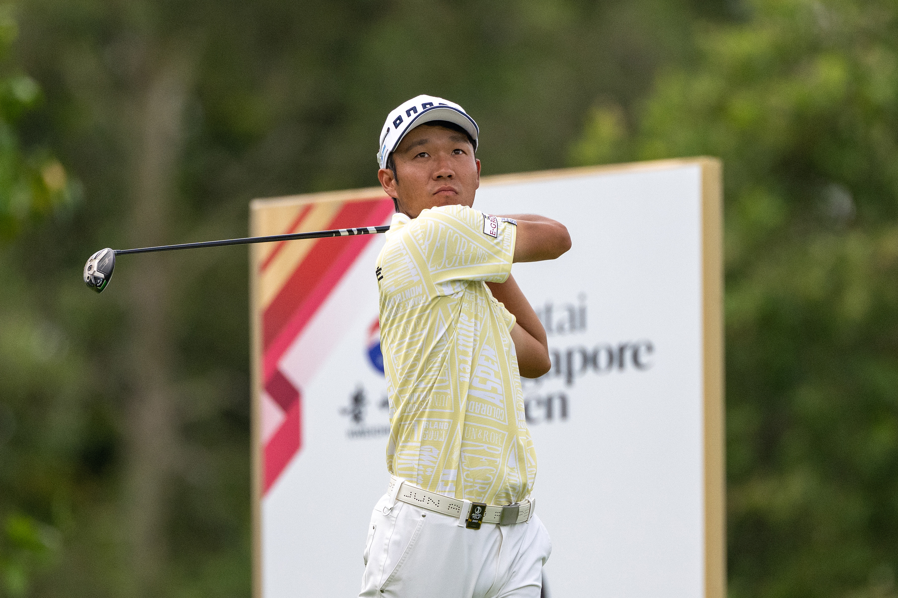 Yosuke Asaji watches his tee shot with a driver