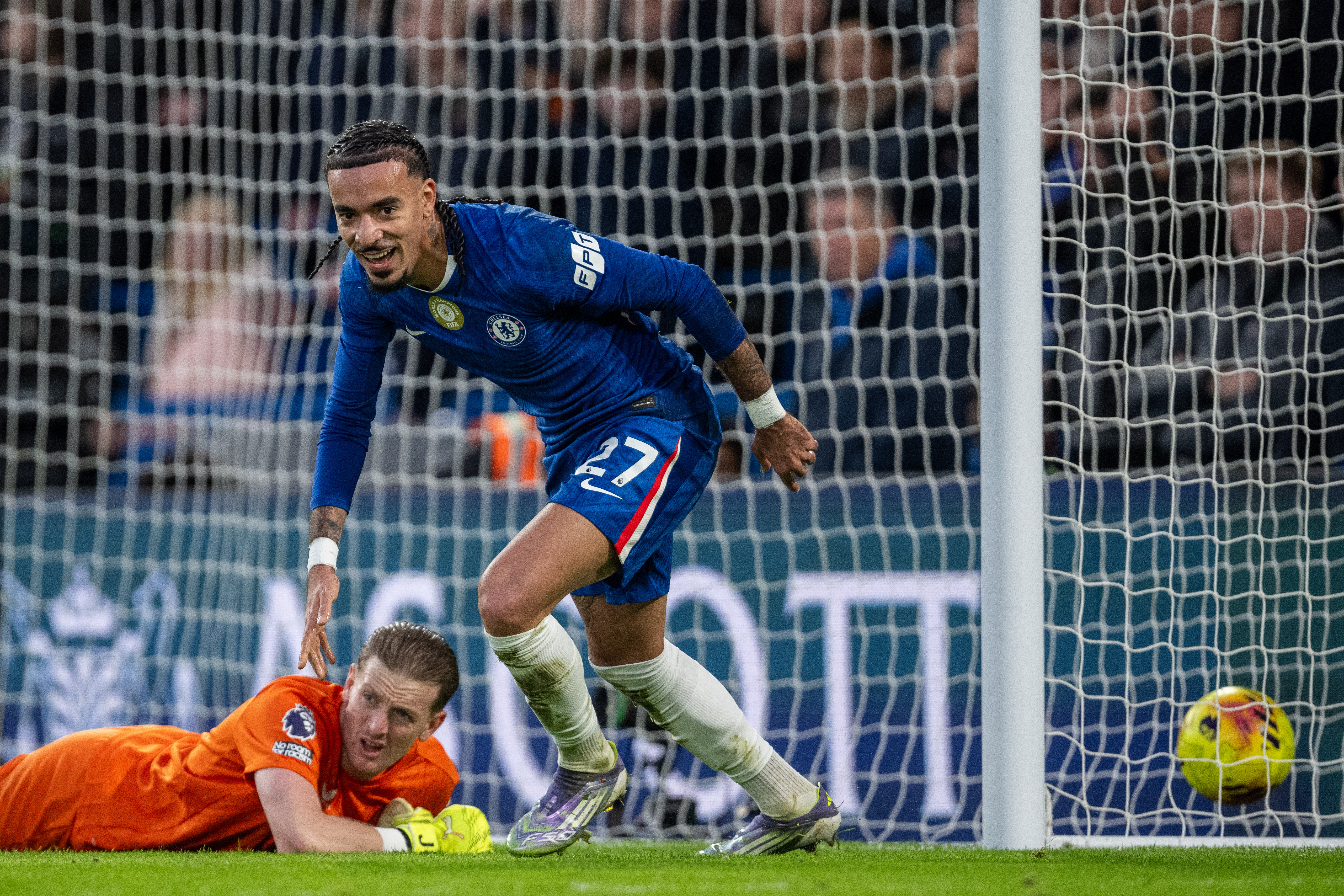 Malo Gusto of Chelsea celebrating his goal as Everton's goalkeeper Jordan Pickford lies on the ground.