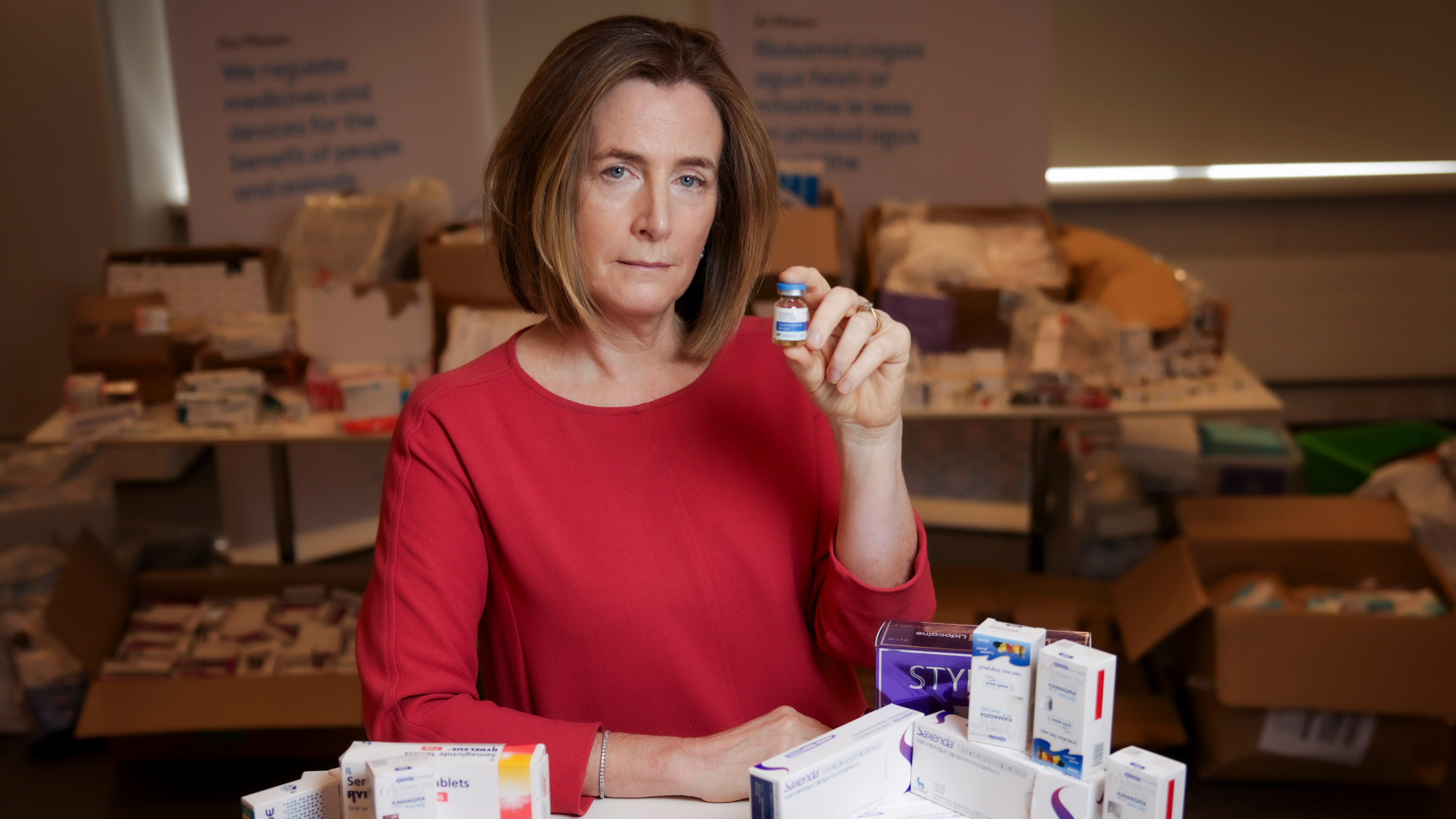 Grainne Power, Director of Compliance, HPRA, holds up a vial of medication, surrounded by boxes of prescription medicines.