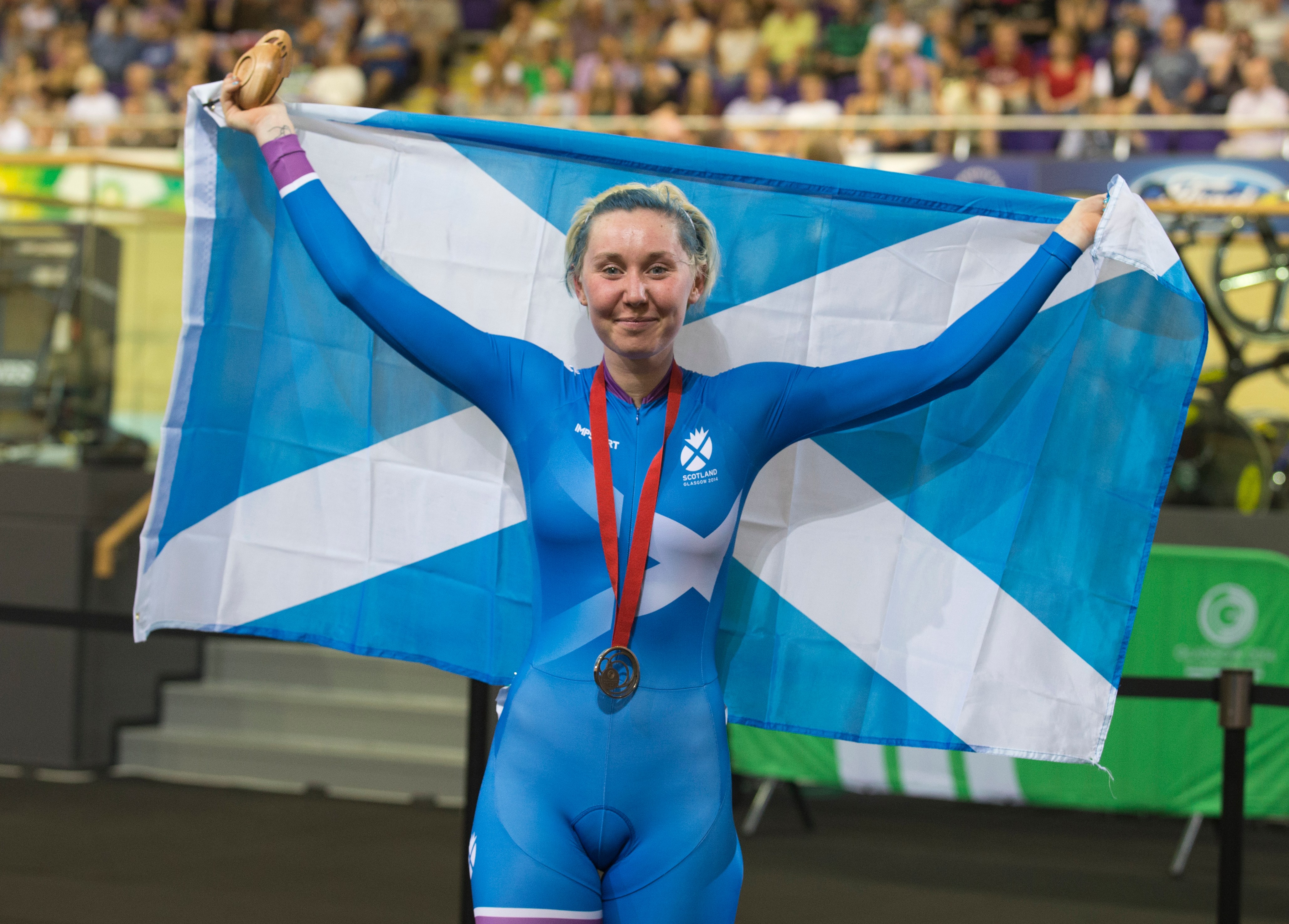 Katie Archibald holding a Scottish flag and her bronze medal from the 2014 Commonwealth Games.