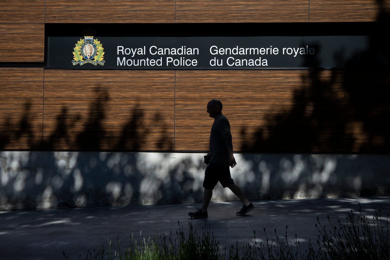 A man walks past a sign that reads 'Royal Canadian Mounted Police'.