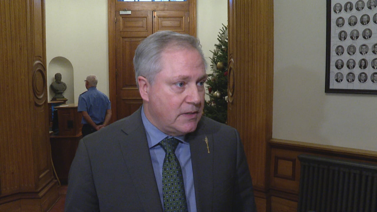 Man in suit stands in doorway.