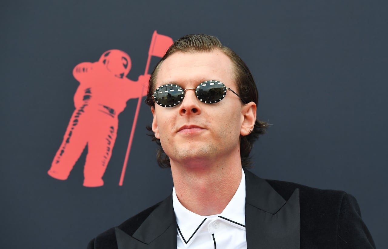 A man wearing sunglasses is shown outside of a music event.