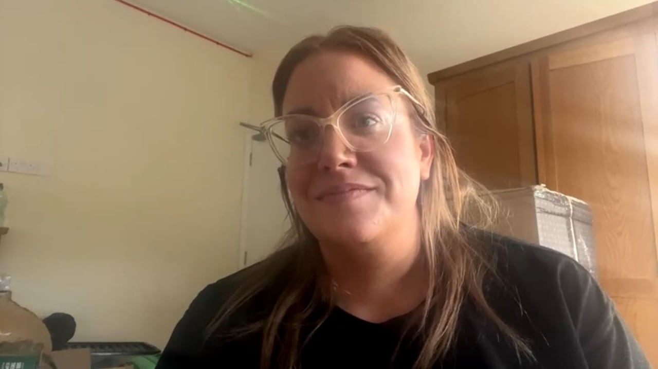 A woman with brown hair wearing a black sweater and glasses