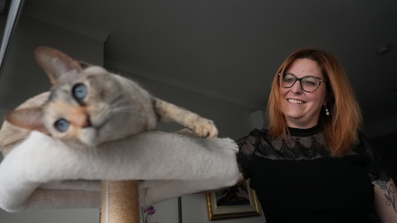 A woman smiles as she pets her cat 