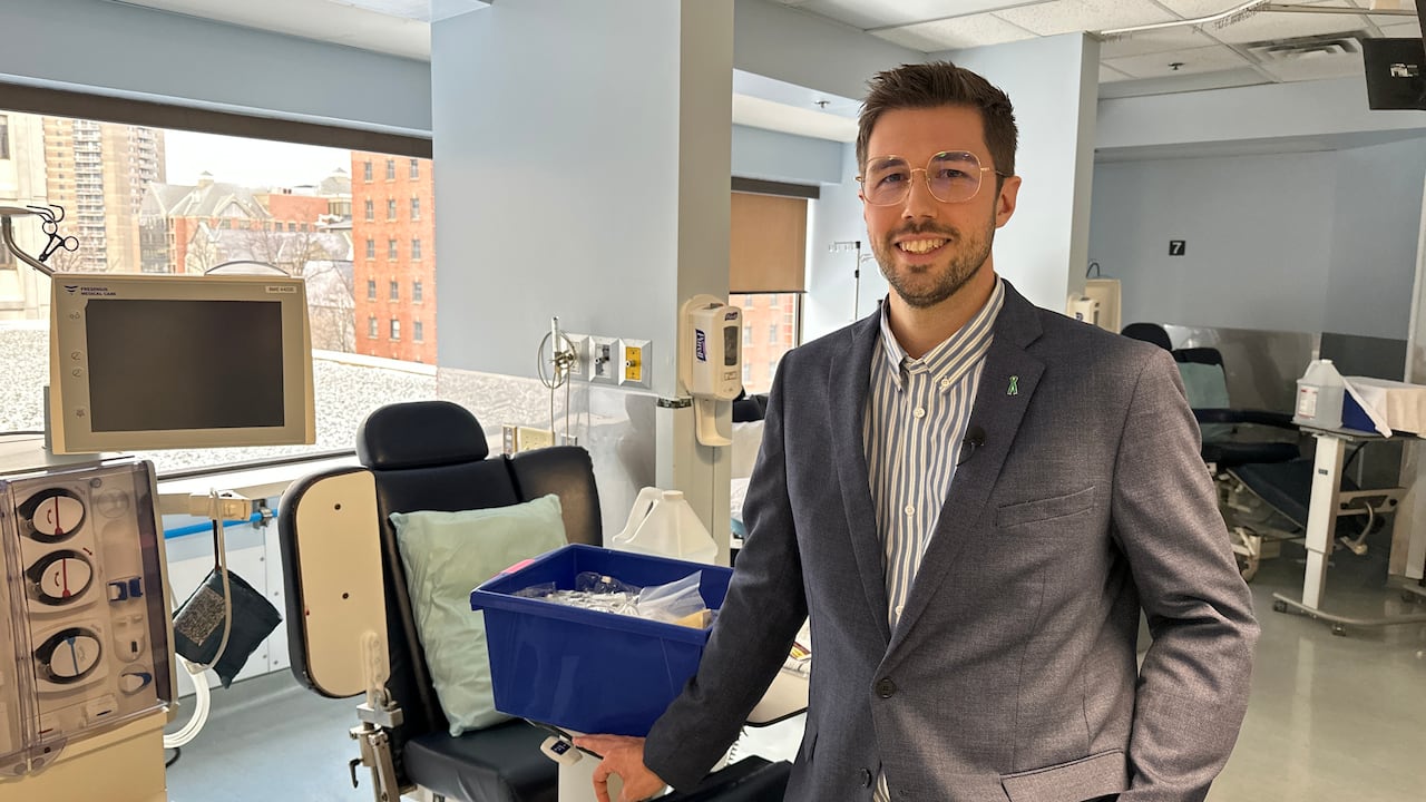 Doctor wearing glasses and a blazer poses beside a dialysis machine at a Halifax hospital.