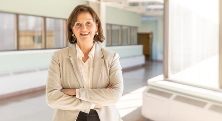 Medium shot of woman smiling at camera with arms crossed