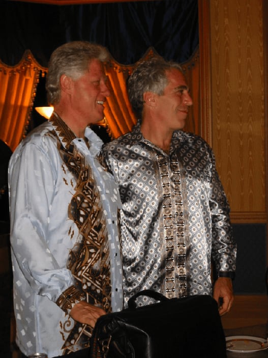 Two grey-haired men smile in similar shirts.
