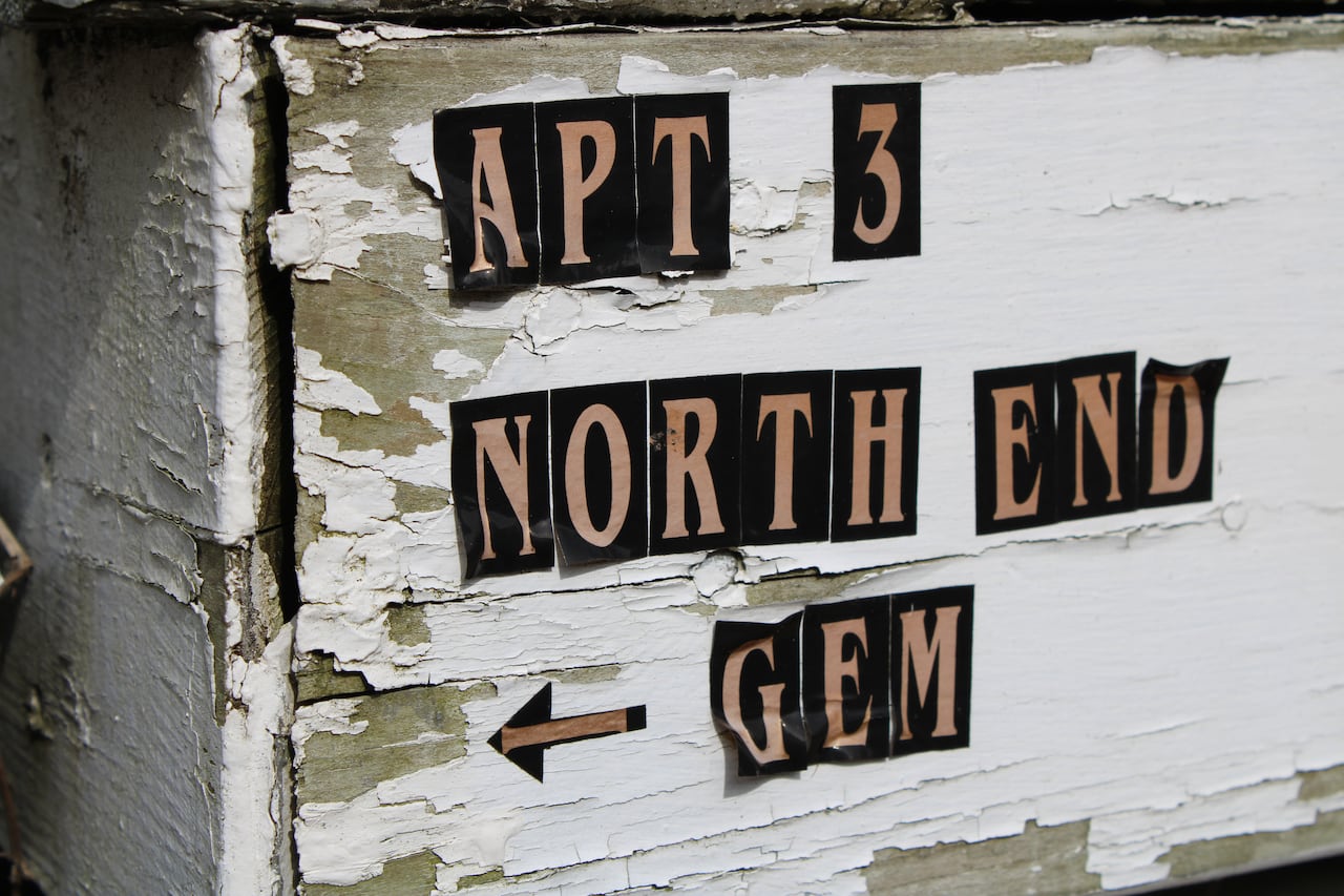 tan colored letters outlined in black on a mailbox with white peeling paint say Apt 3 North End Gem