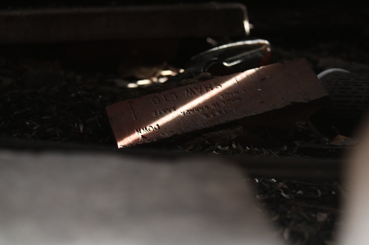 a brick in shadow with a ray of light across it. Words SHAW LTD are inscribed on it