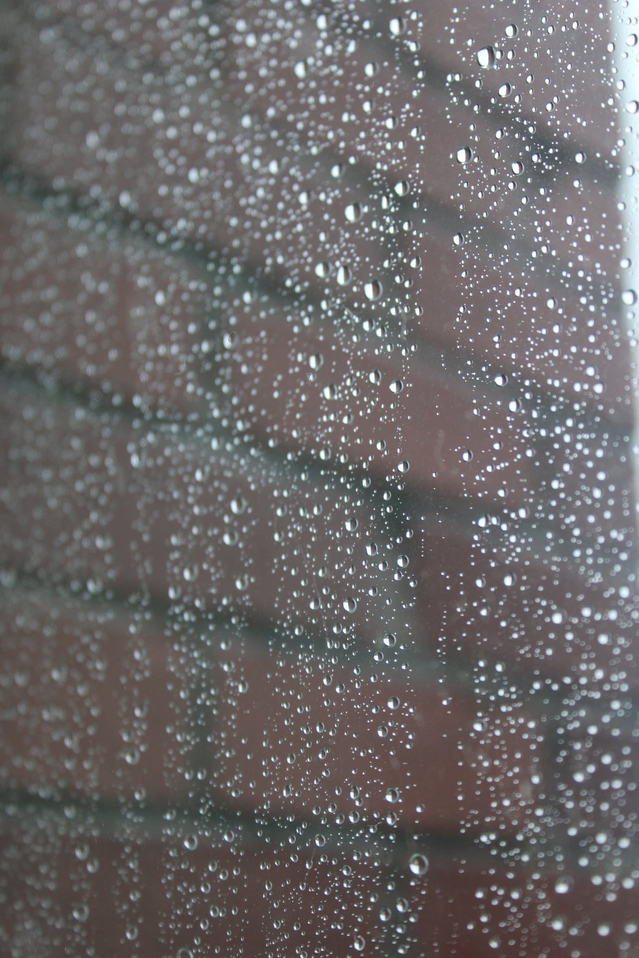 raindrops on a window with a brick wall in the background