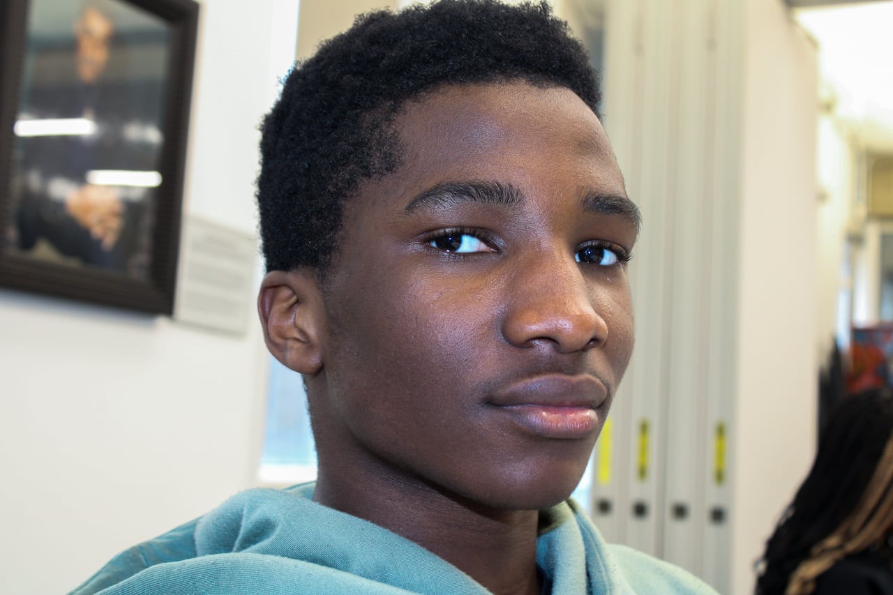 up close photo of a black boy looking at the camera wearing a green sweatshirt