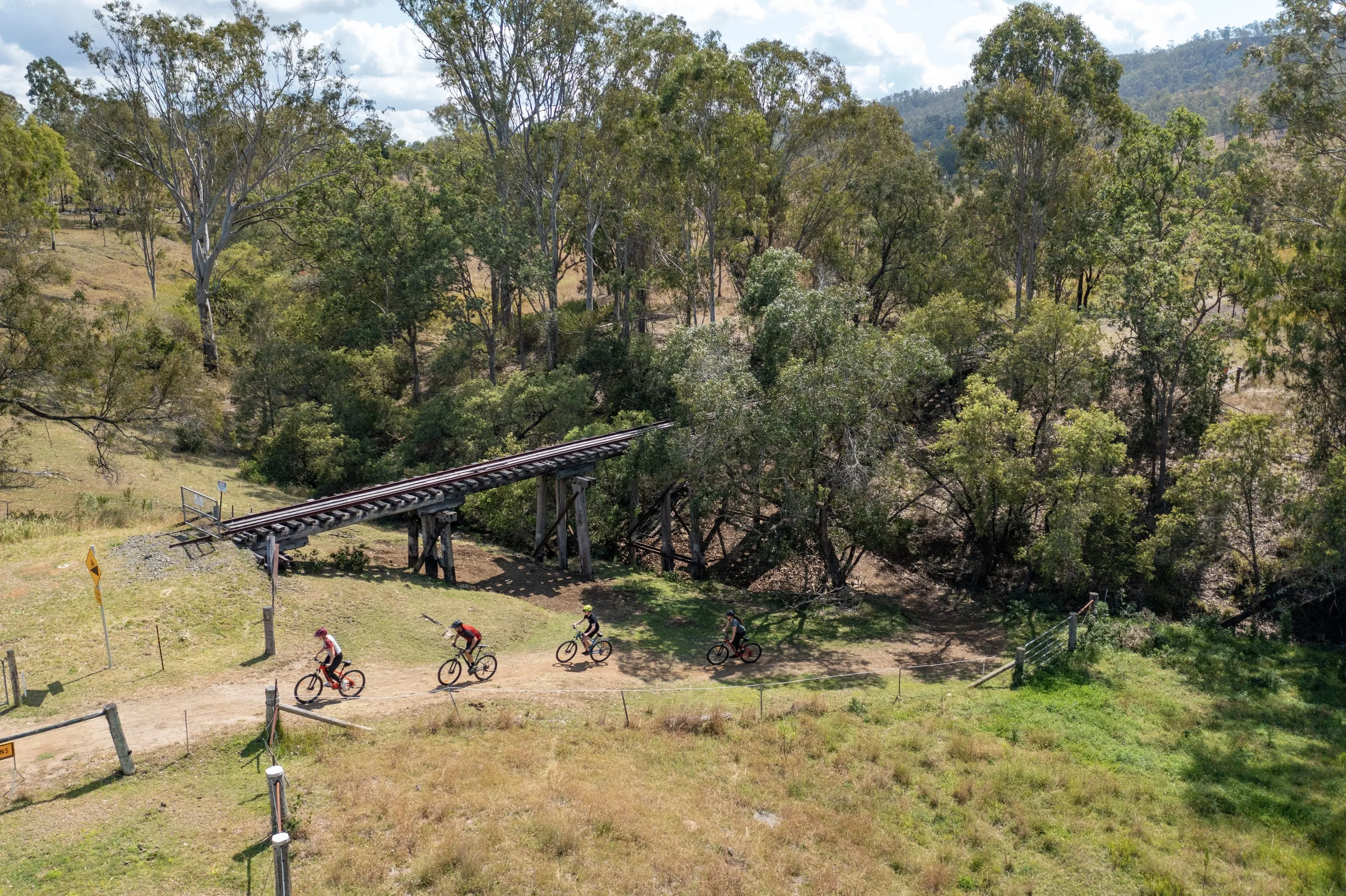 Aerial view of bike riders riding past a historic railway bridge