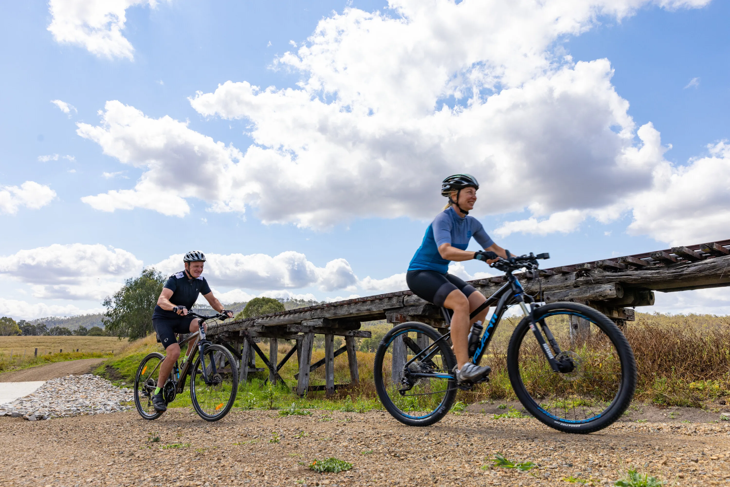 Couple riding their bikes past a historic railway bridge