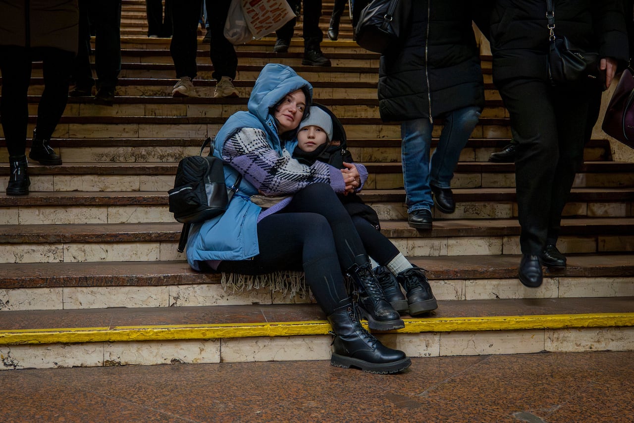 Adult and child are seen embracing in a rail station-turned-bomb shelter