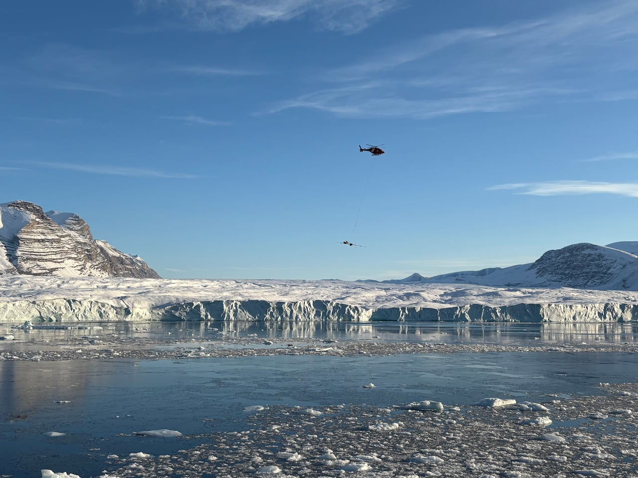 helicopter flies over glacier
