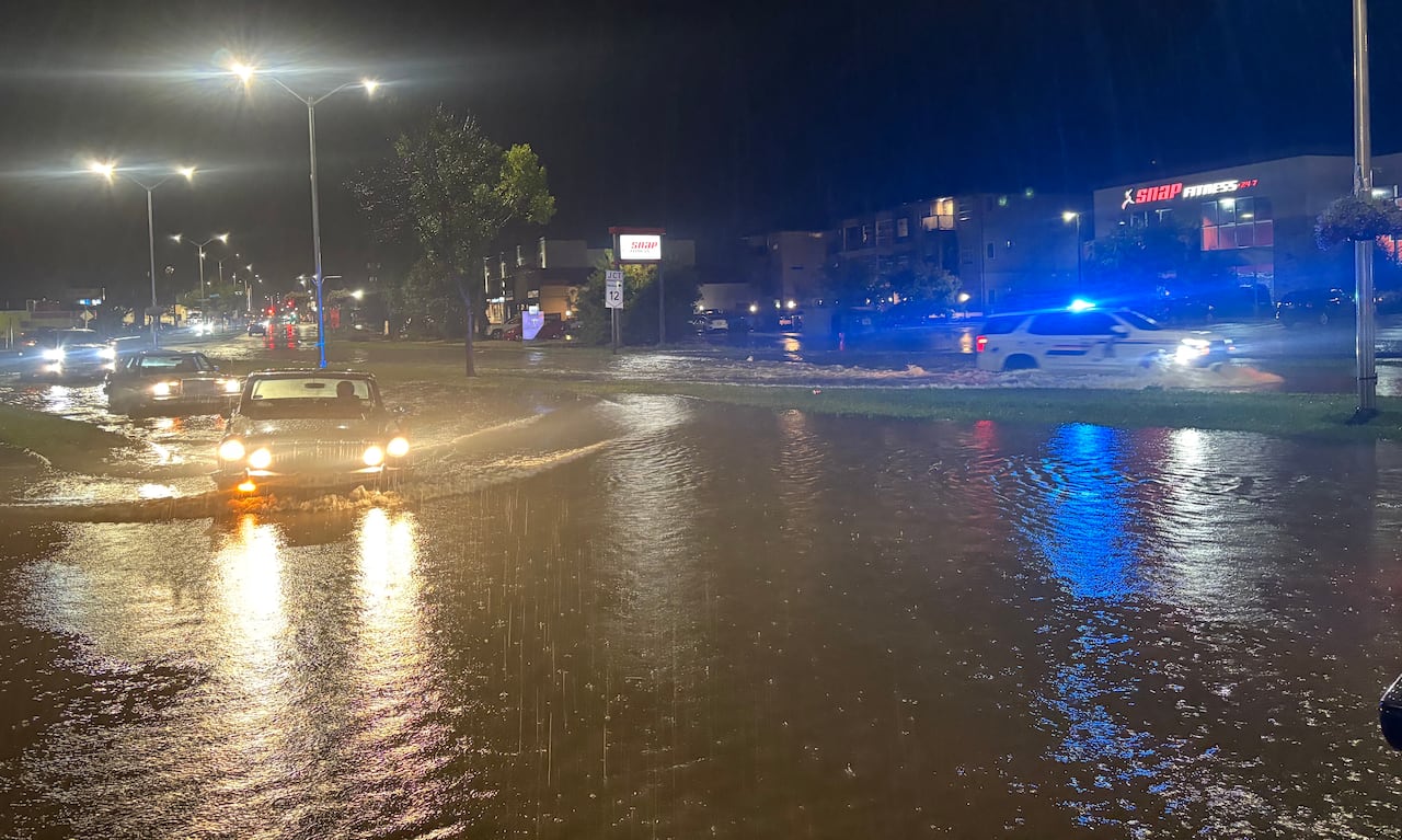 Vehicles including a police SUV drive through flooded streets.