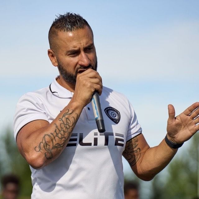 Soccer coach stands at podium speaking to crowd