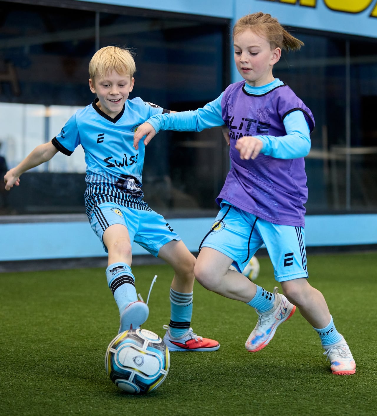 Two young soccer players compete for control of the ball