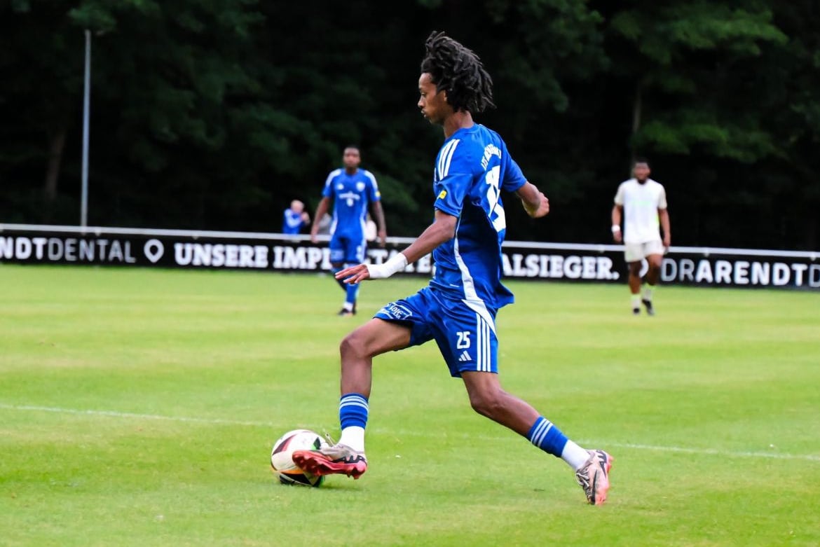 Soccer player kicks ball down field.