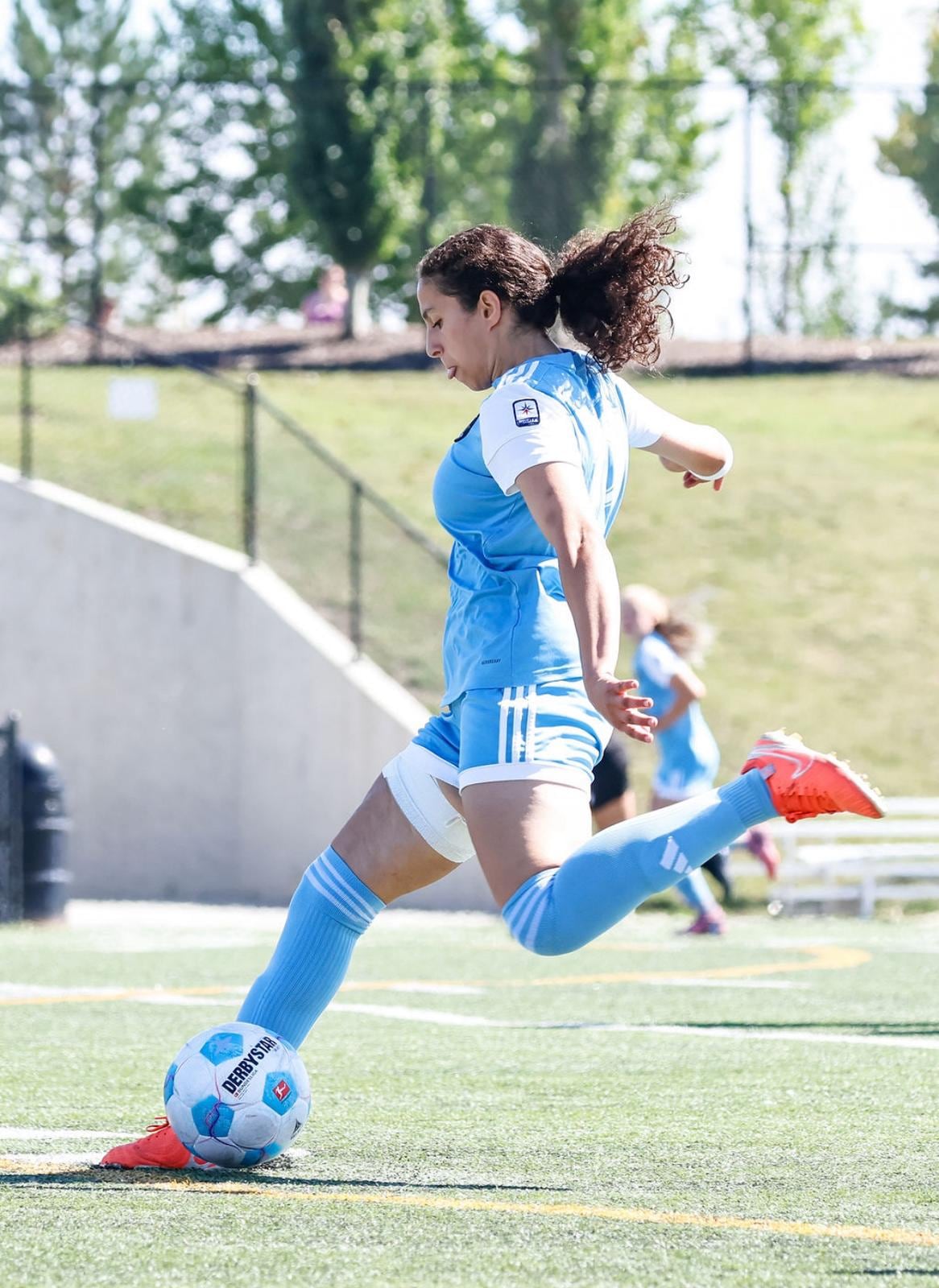 Teenage girl on field kicks ball