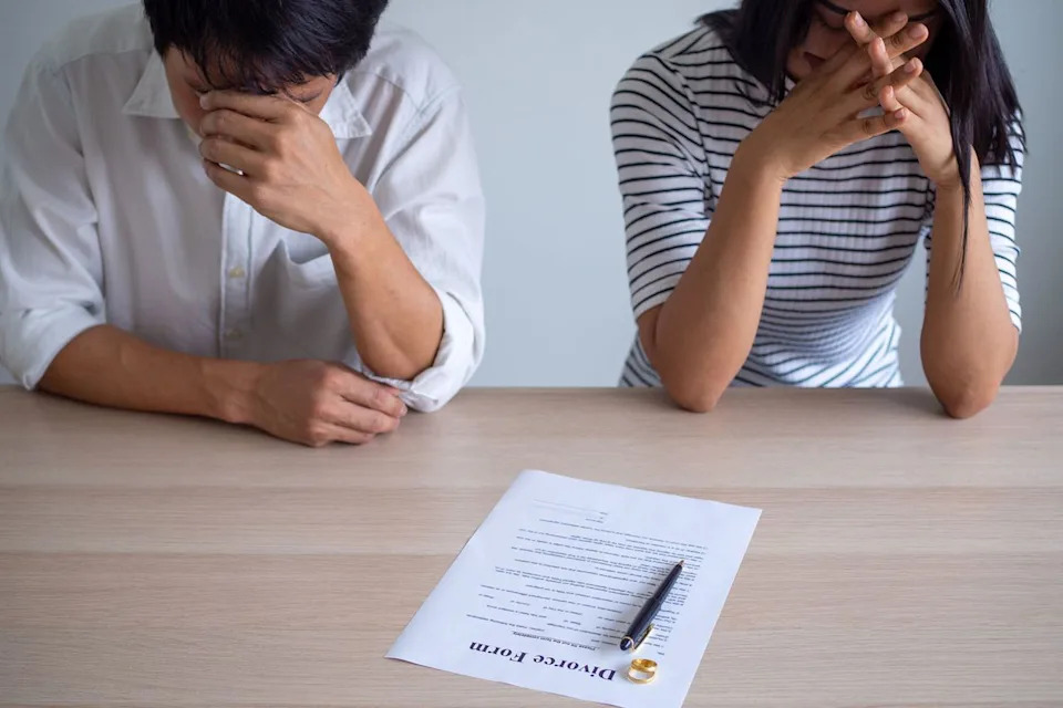 Getty Stock image of a stressed couple signing divorce documents.