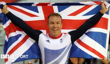Sir Chris Hoy holding up two Olympic gold medals